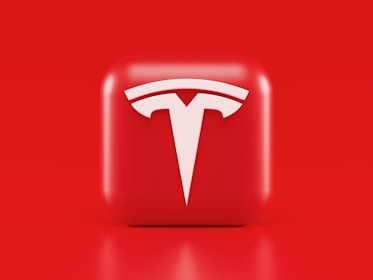 A glossy, red 3D square icon features a white, stylized 'T' logo with a futuristic and sleek design. The background is also solid red, creating a visually striking contrast.