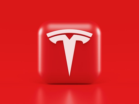 A glossy, red 3D square icon features a white, stylized 'T' logo with a futuristic and sleek design. The background is also solid red, creating a visually striking contrast.