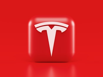 A glossy, red 3D square icon features a white, stylized 'T' logo with a futuristic and sleek design. The background is also solid red, creating a visually striking contrast.