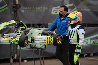Savannah Maddox in her racing suit, helmet on, next to her kart on the track.