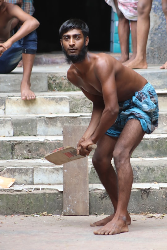 man in blue shorts sitting on concrete stairs in Dhaka Bangladesh