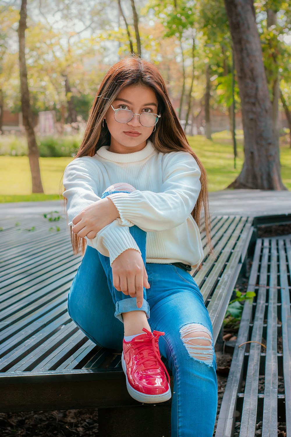 woman in white long sleeve shirt and blue denim shorts sitting on brown wooden bench during