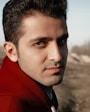 man in red hoodie standing on brown field during daytime