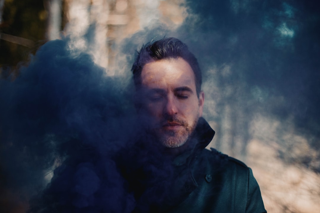 man in green jacket with white smoke in his face