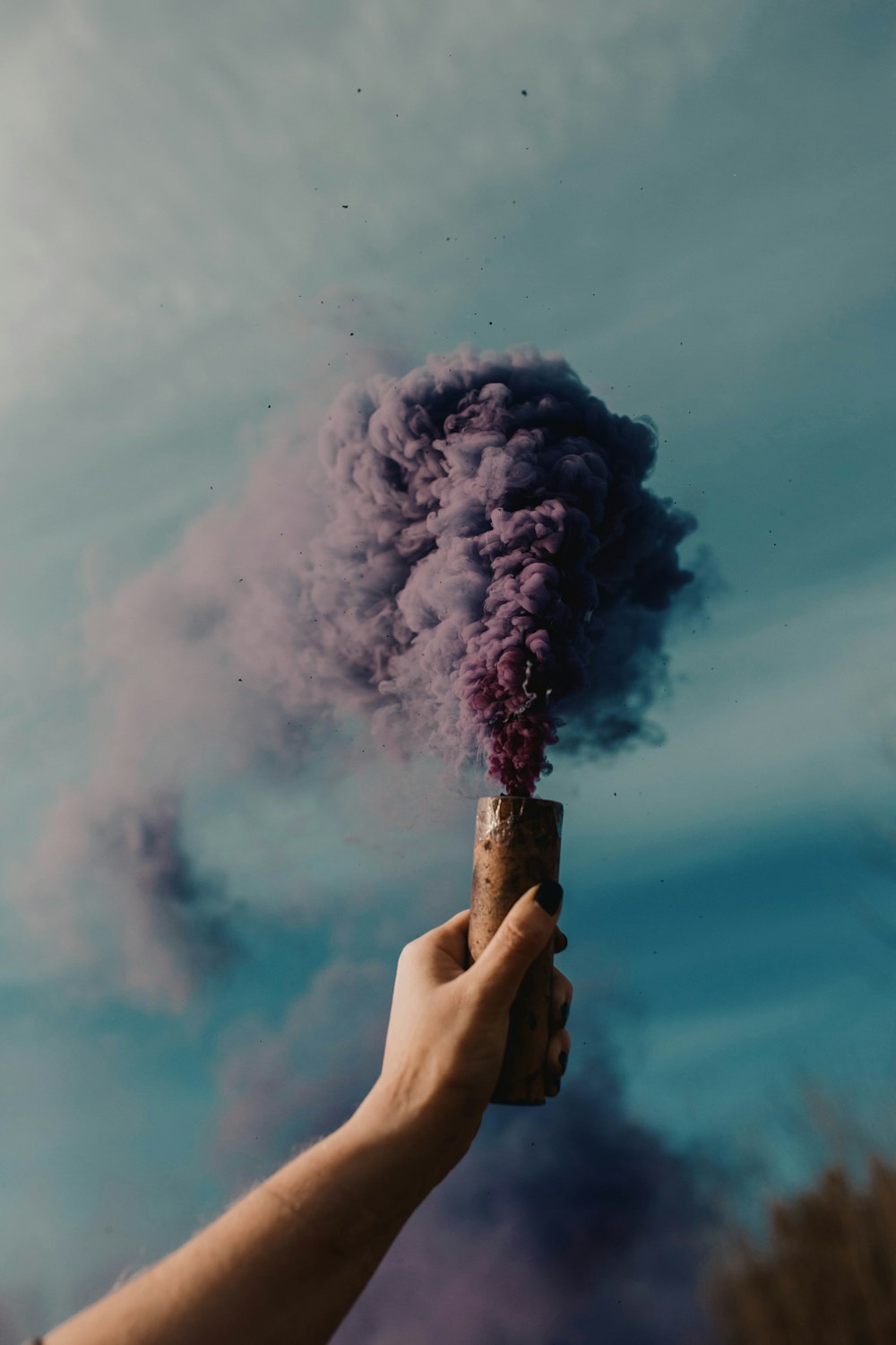 person holding blue smoke on brown wooden stick