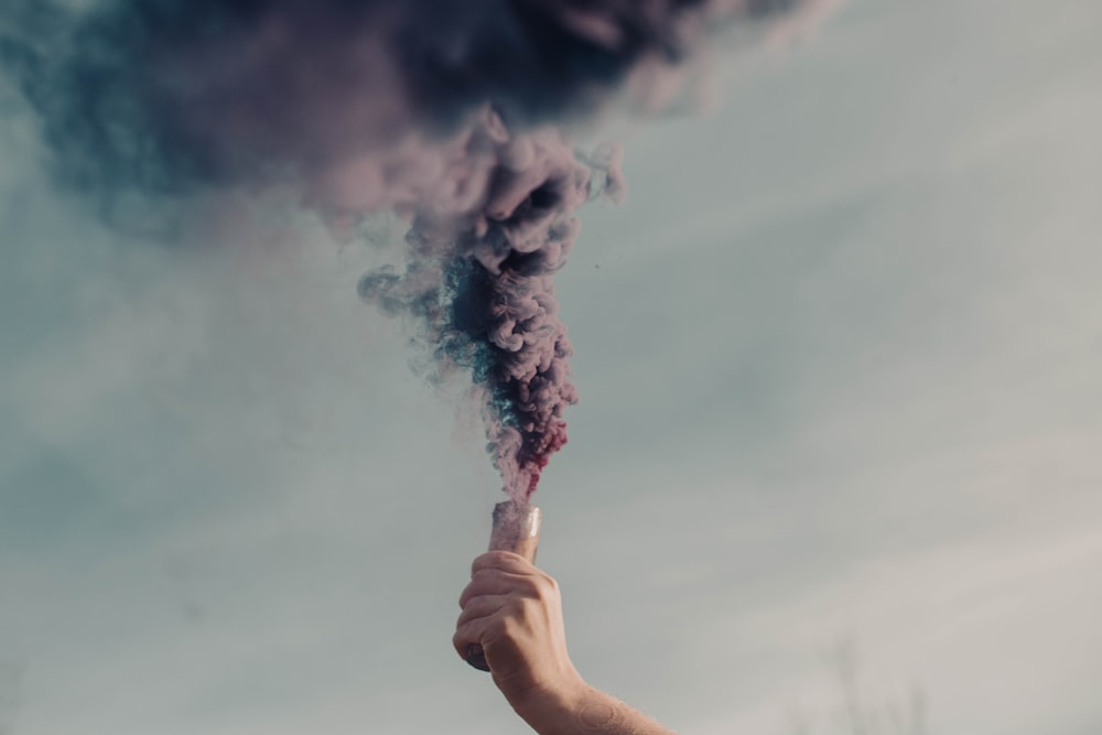 person holding white smoke during daytime