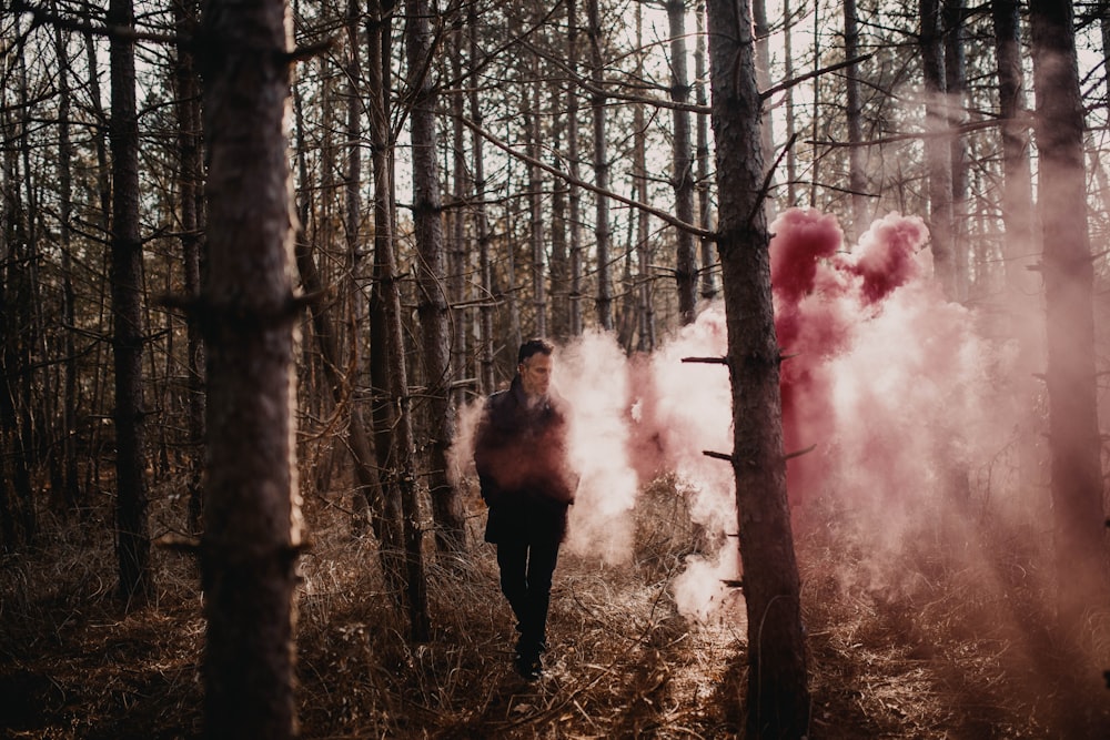 woman in black jacket standing on forest with red smoke