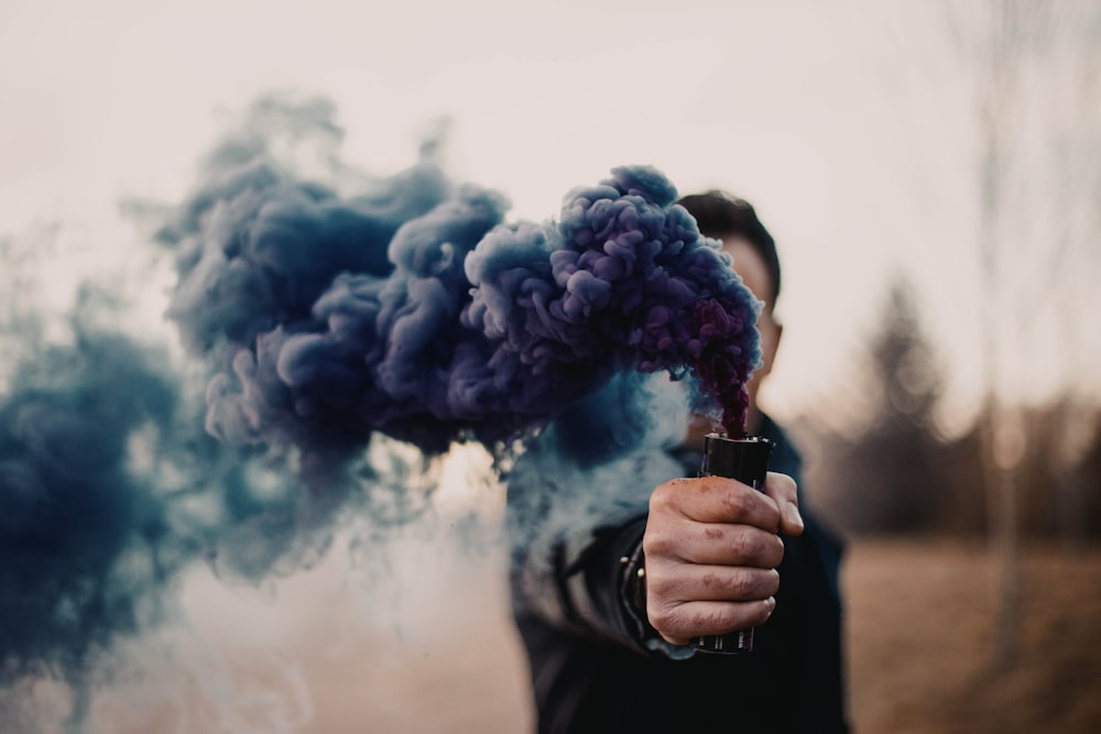 person holding blue smoke during daytime