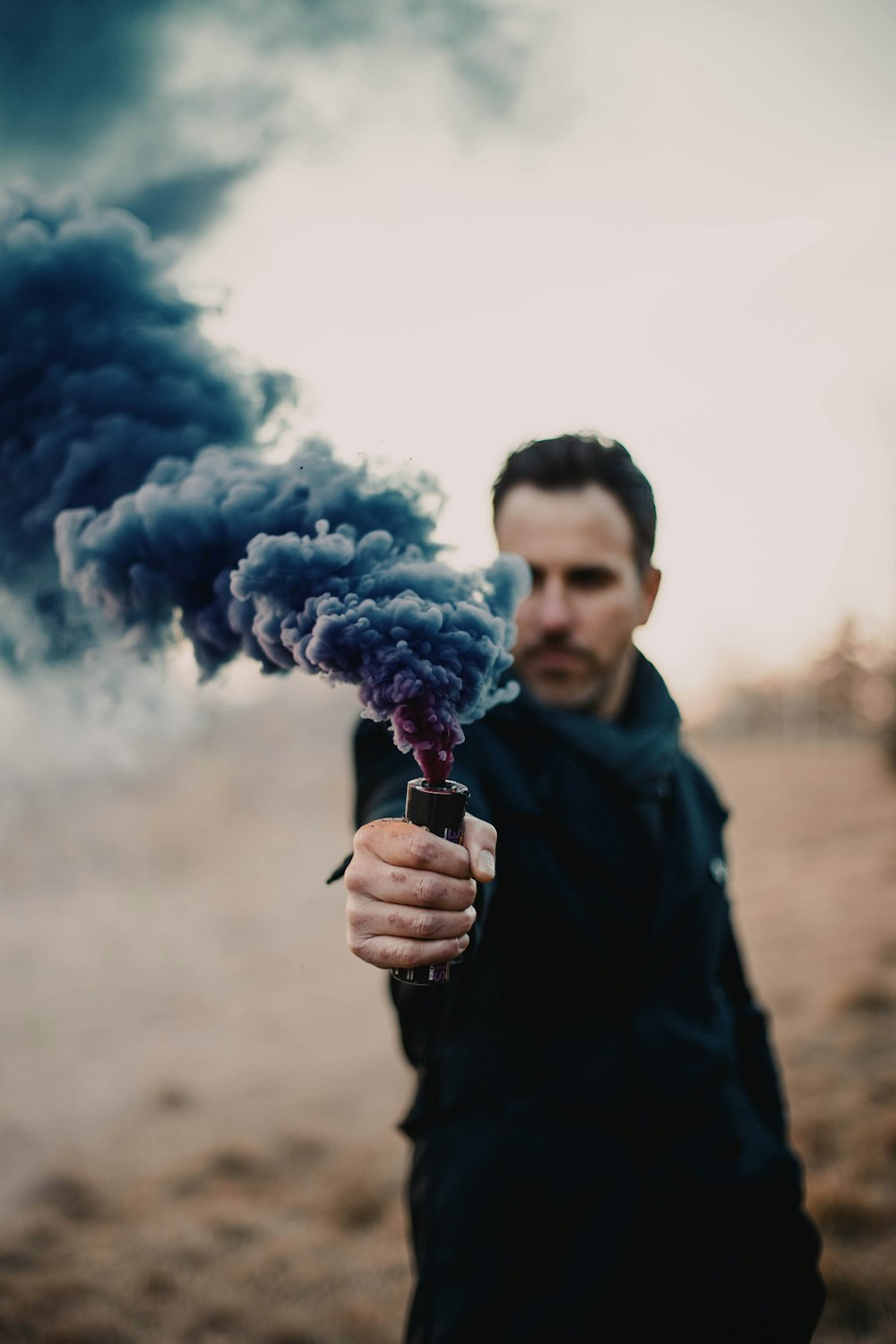 man in black jacket holding blue smoke