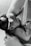 A black and white image of an infant breastfeeding. The baby is wearing a delicate headband and is held gently. The adult's arm is visible, cradling the child in a nurturing manner.