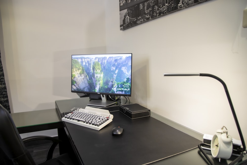 black flat screen computer monitor on black wooden desk