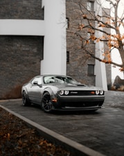 silver porsche 911 parked beside white concrete building during daytime