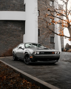 silver porsche 911 parked beside white concrete building during daytime