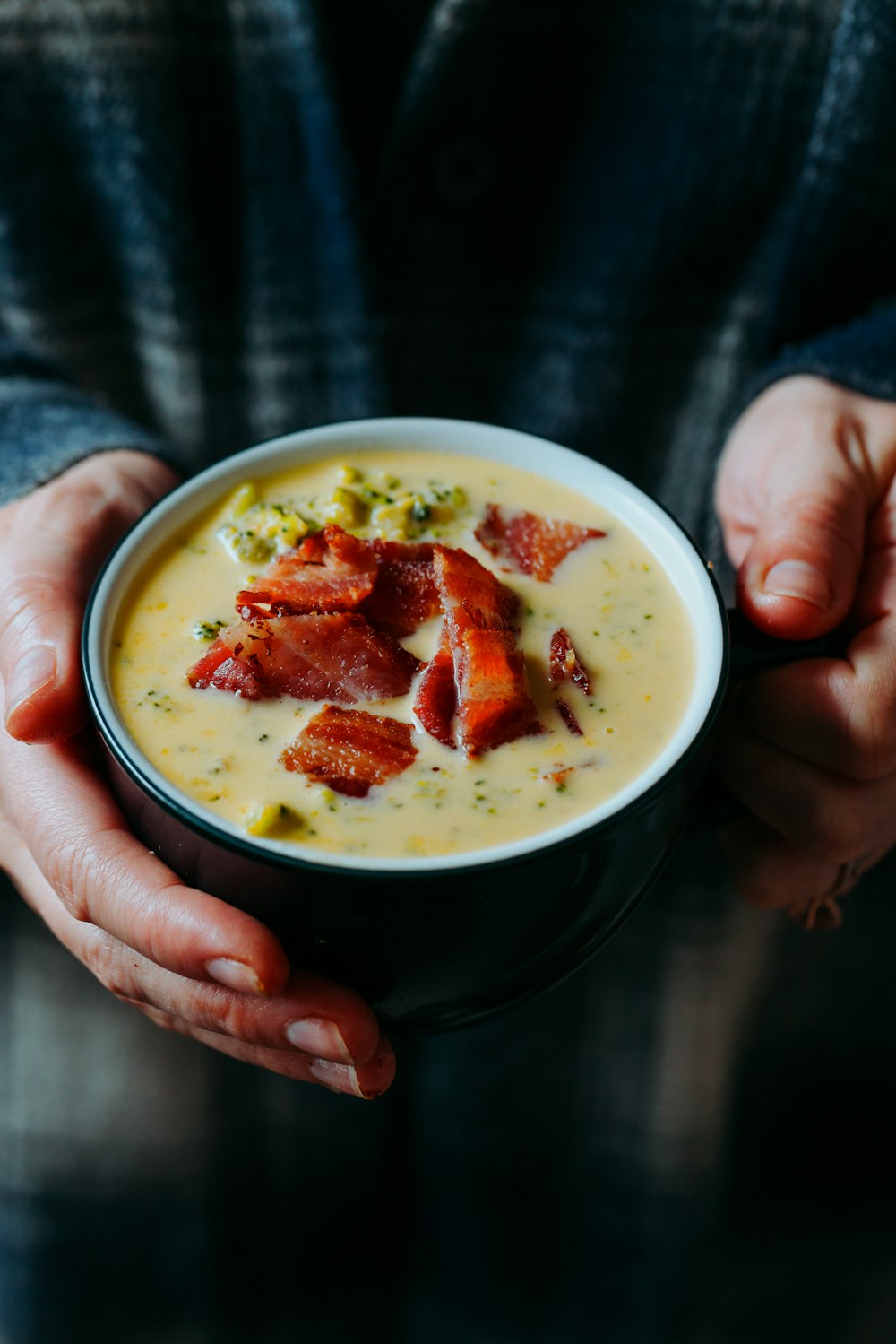 Person mit weißer Keramikschüssel mit Suppe