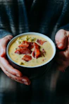 person holding white ceramic bowl with soup