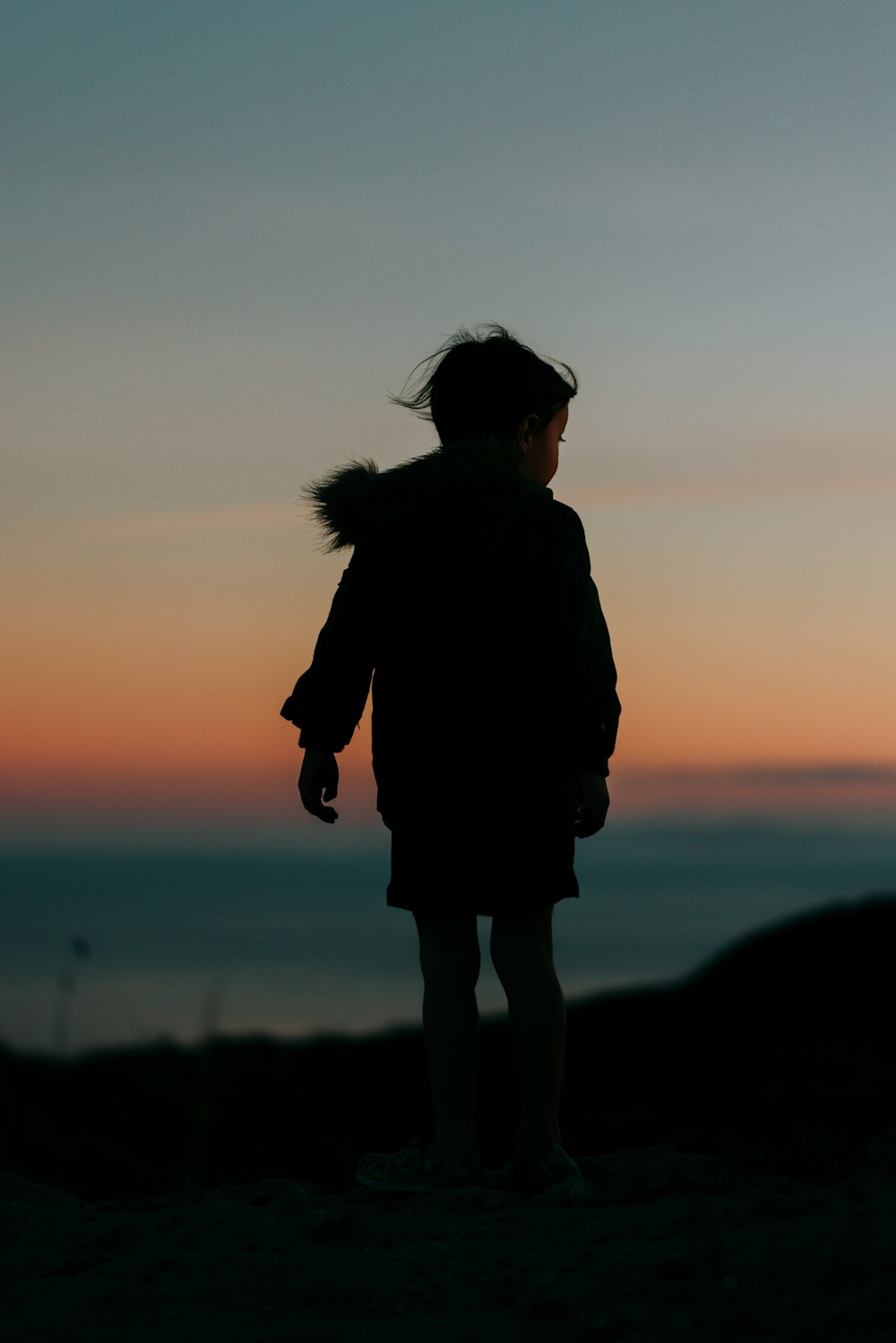 silhouette of woman standing on hill during sunset