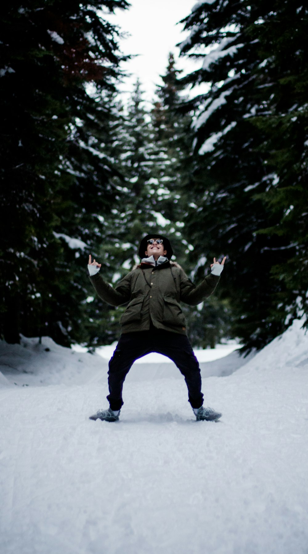 Hombre con chaqueta verde y pantalones negros sentado en el suelo cubierto de nieve