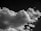 A striking black-and-white image featuring a large, fluffy cloud with various textures and shapes against a dark sky.