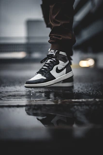 Side view of a black safety shoe with slip-resistant sole on a wet surface.
