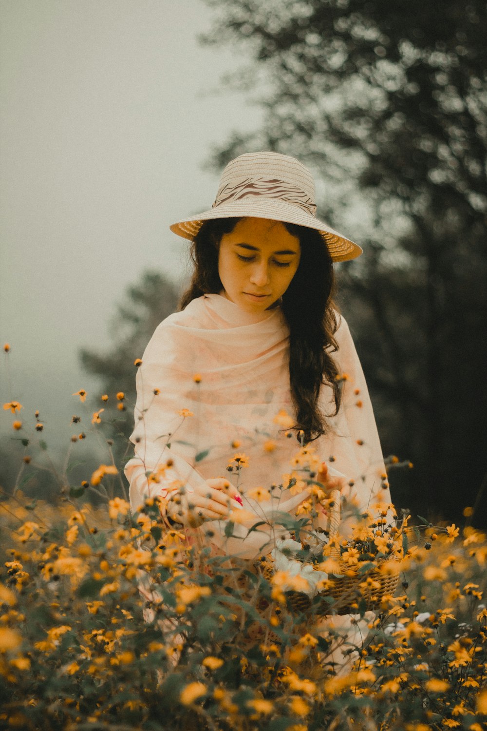 낮 동안 노란 꽃밭에 서 있는 흰색과 갈색 꽃무늬 긴팔 셔츠를 입은 여자