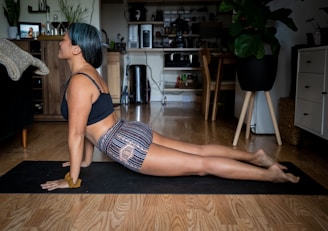 woman in black tank top and black and white striped shorts stretching her lower back
