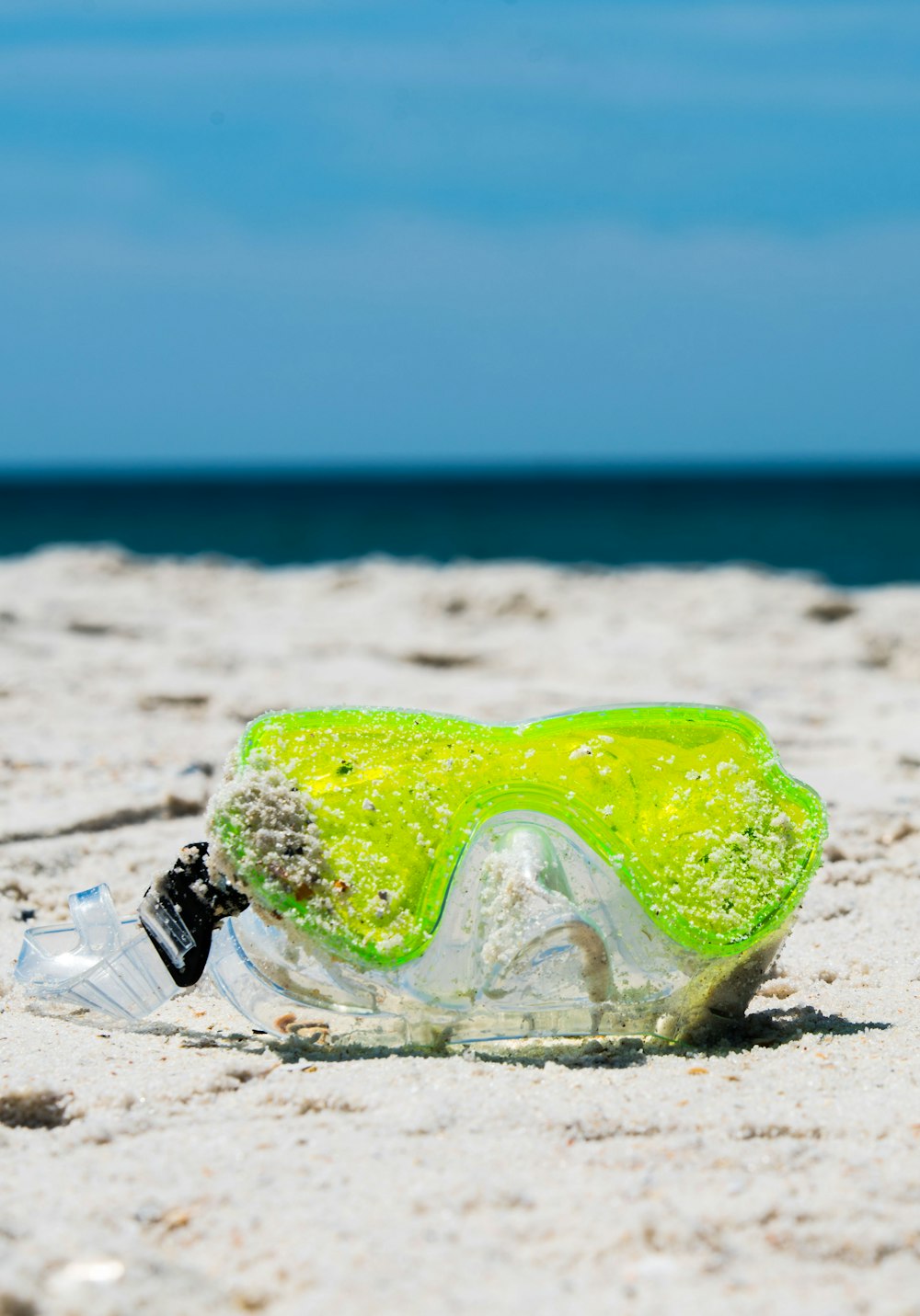 green and black water goggles on white sand beach during daytime
