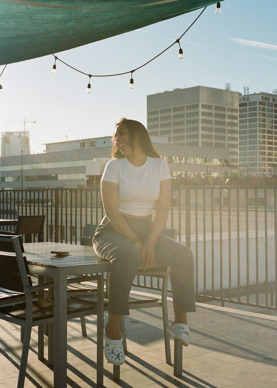 woman in white tank top and gray pants sitting on black wooden chair