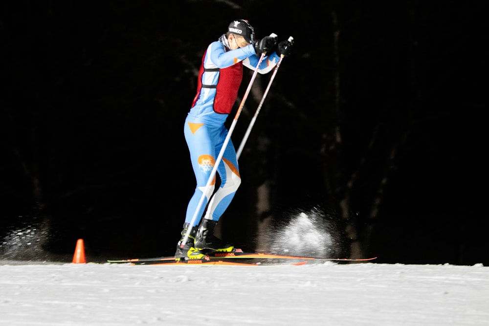 Hombre en chaqueta azul y roja y pantalones azules montando en snowboard