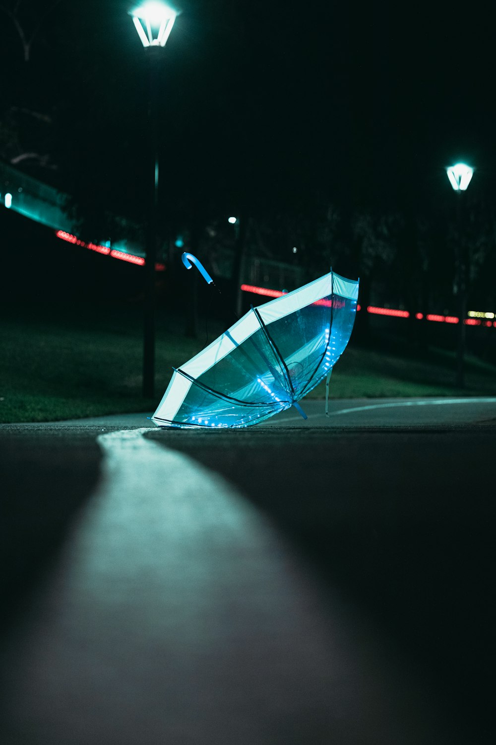 blue umbrella on gray asphalt road during night time