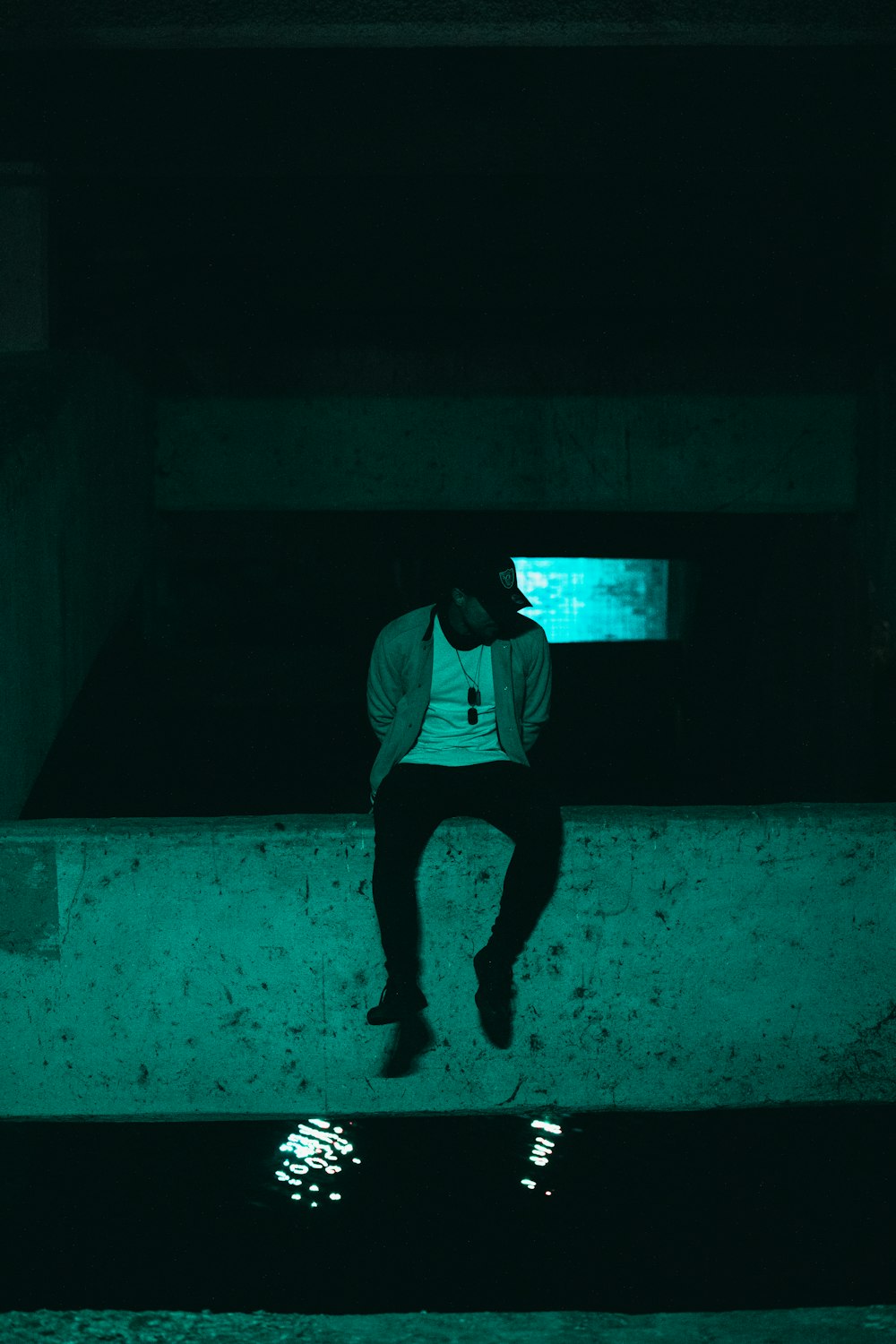 man in white t-shirt and black pants standing on gray concrete floor