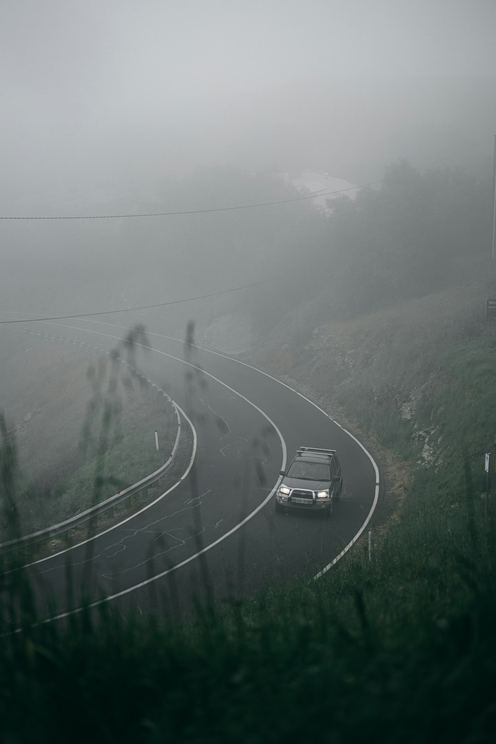 Voitures sur la route entre un champ d’herbe verte par temps de brouillard