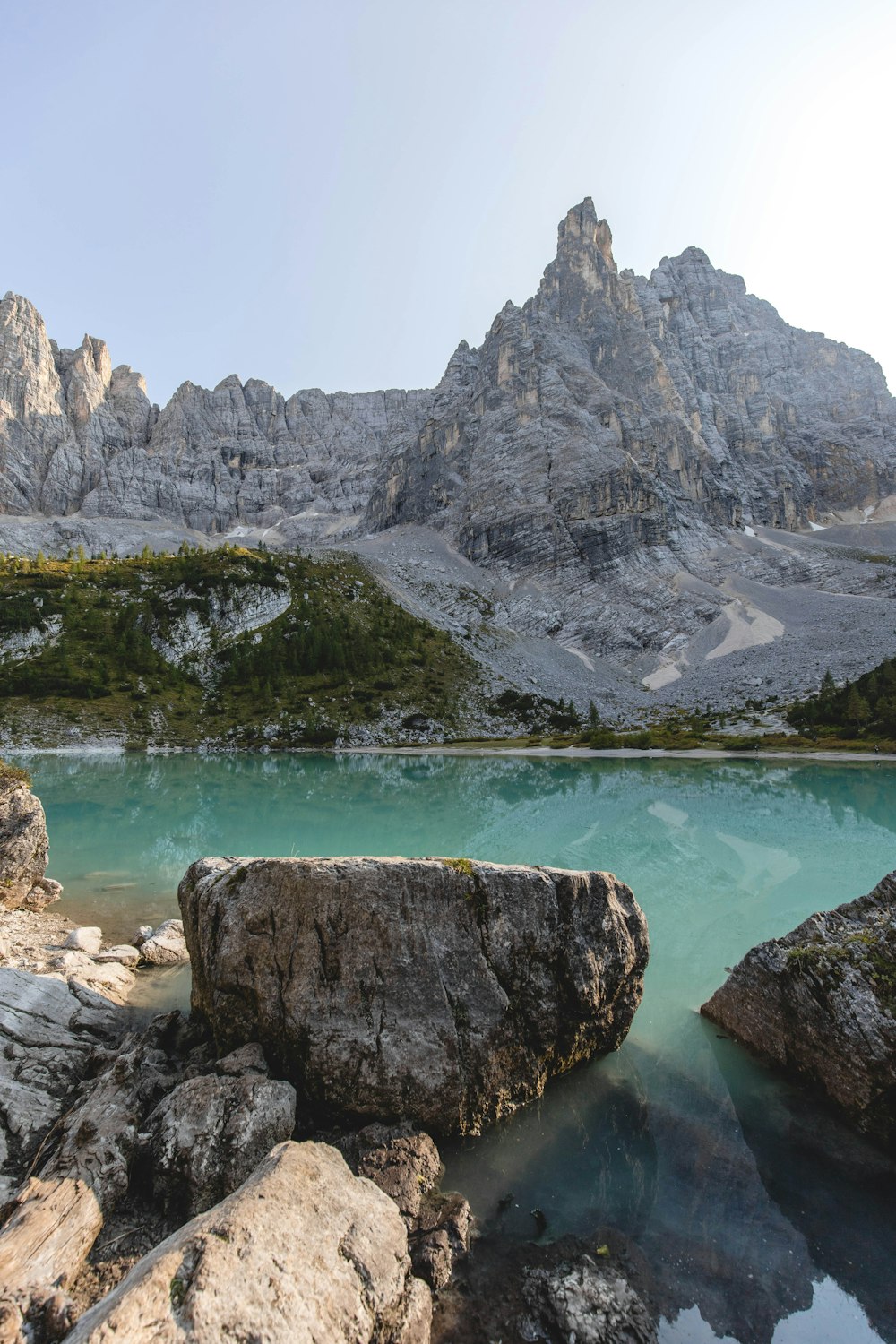 gray rocky mountain beside blue sea under blue sky during daytime