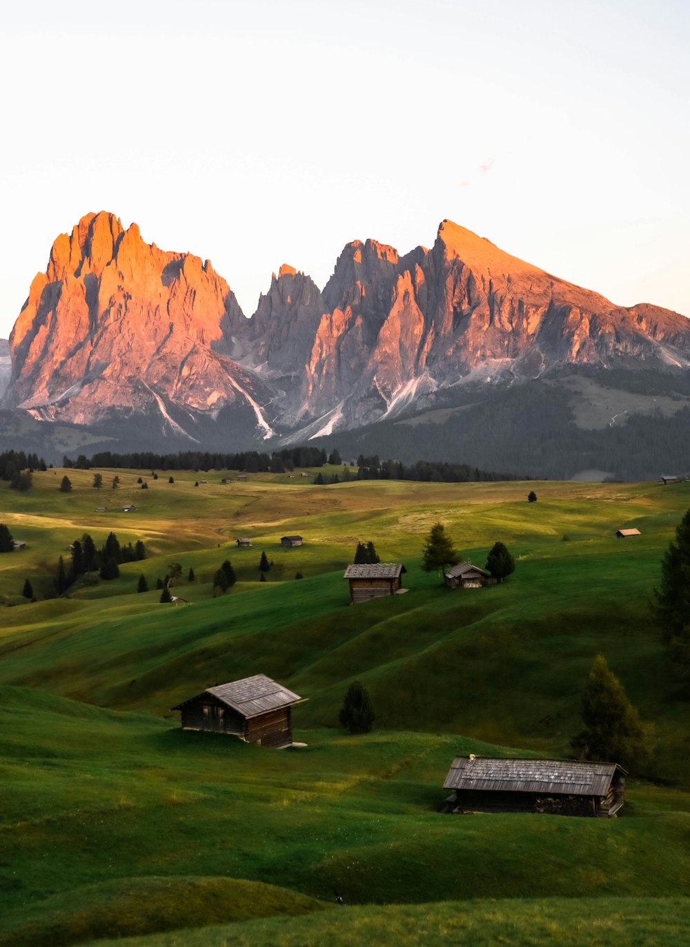 Casa di legno marrone sul campo di erba verde vicino alla montagna rocciosa marrone durante il giorno