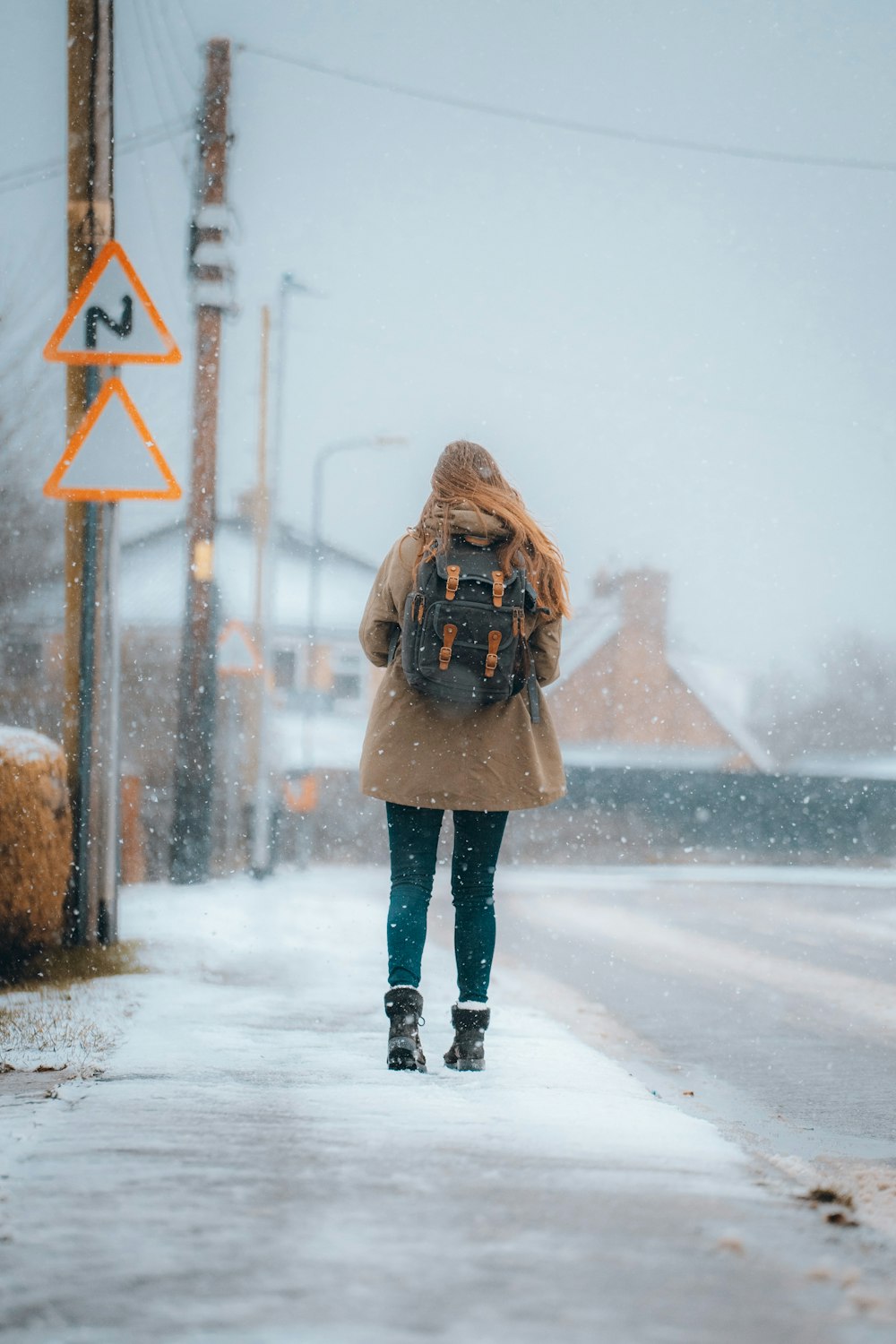 woman in brown coat standing on snow covered ground during daytime