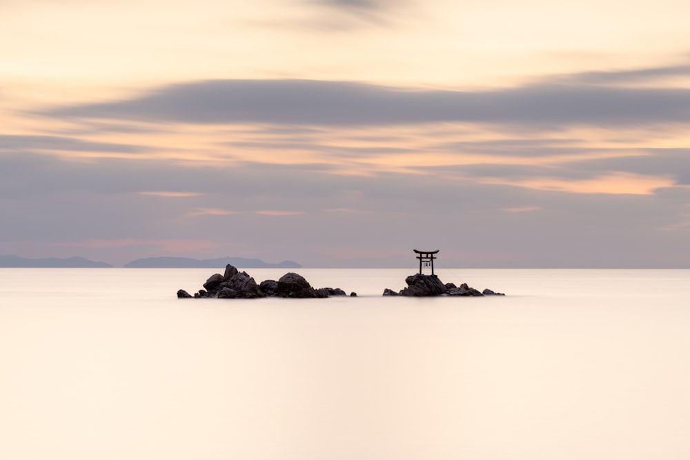 silhouette of rock formation on sea during sunset