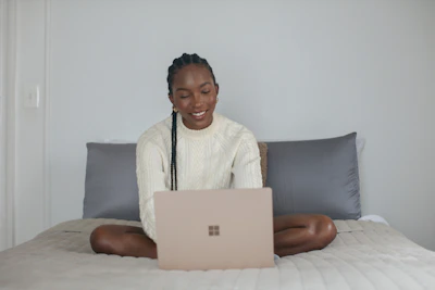 A smiling person filling out their dating profile on a laptop in a cozy home setting.