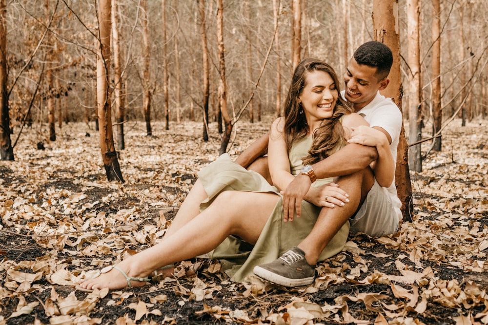 man and woman sitting on ground with dried leaves