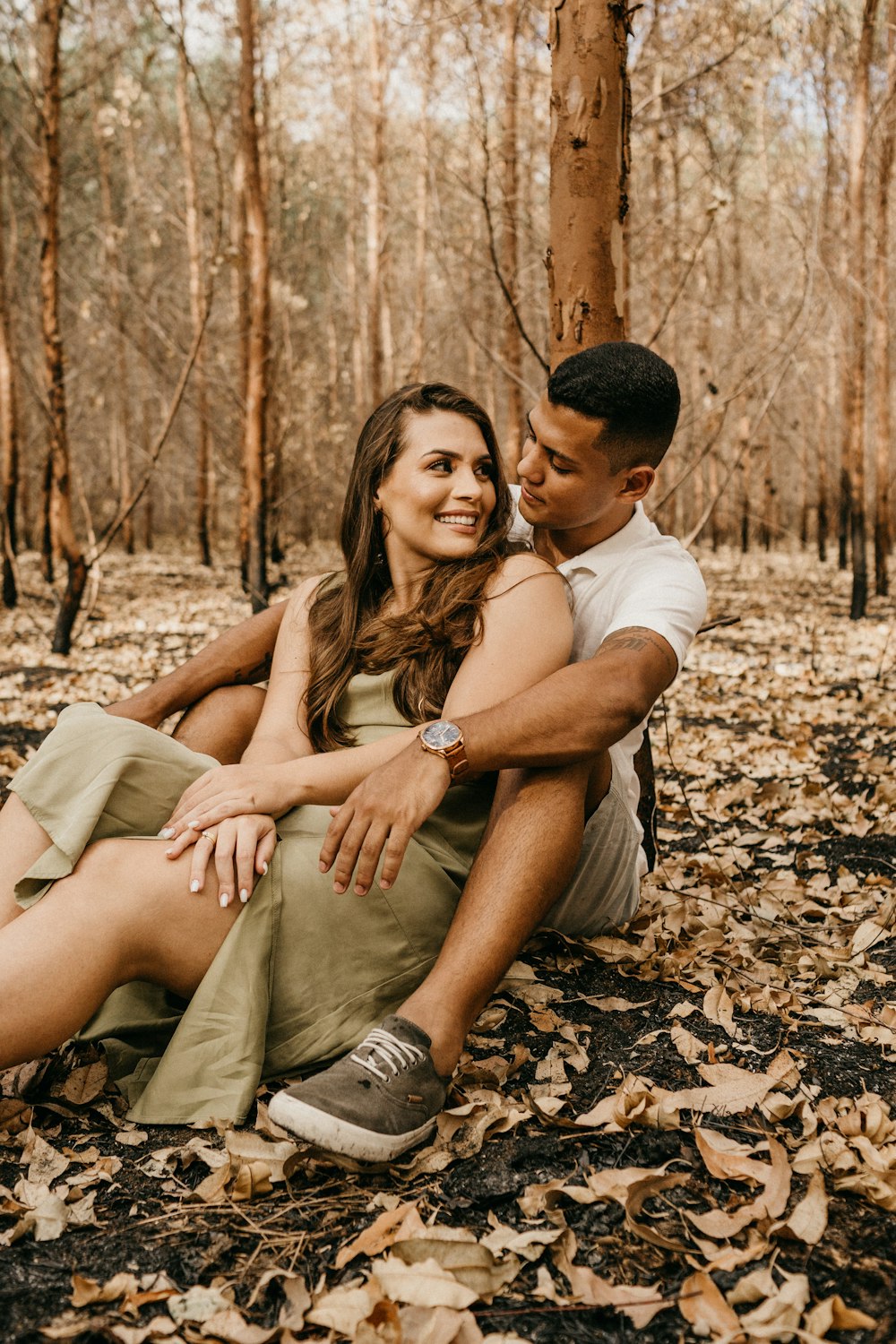 man and woman sitting on ground with dried leaves