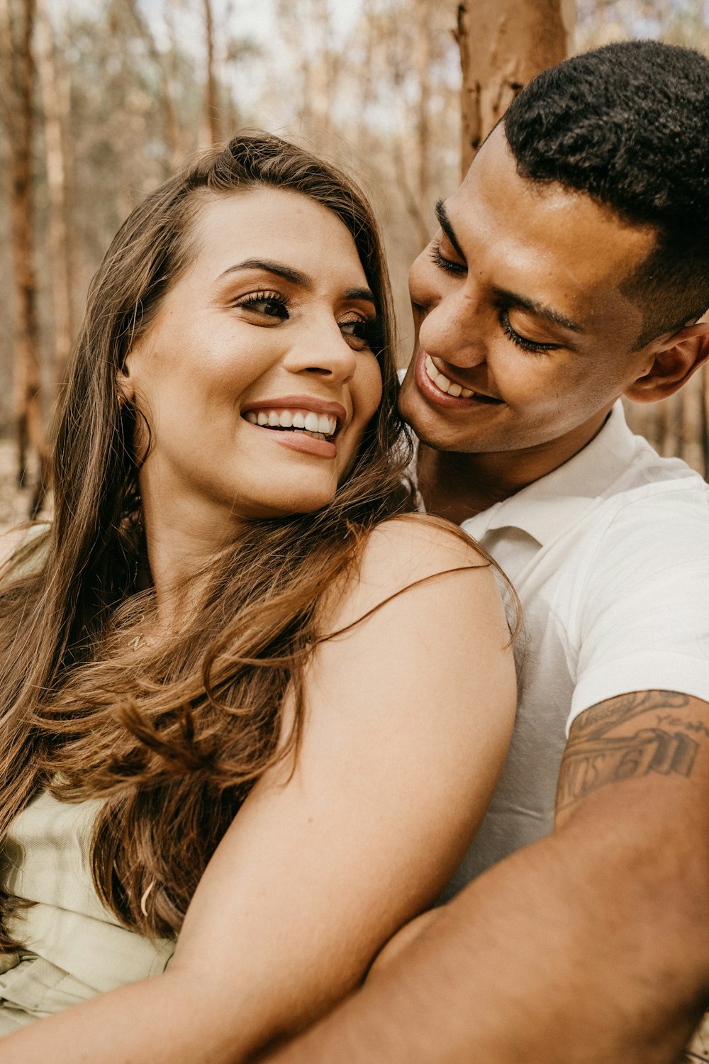 man in white shirt hugging woman in white tank top