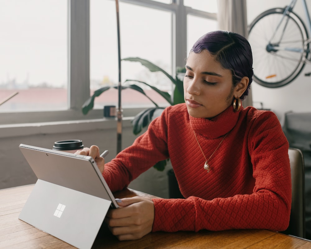 person in red sweater using Surface