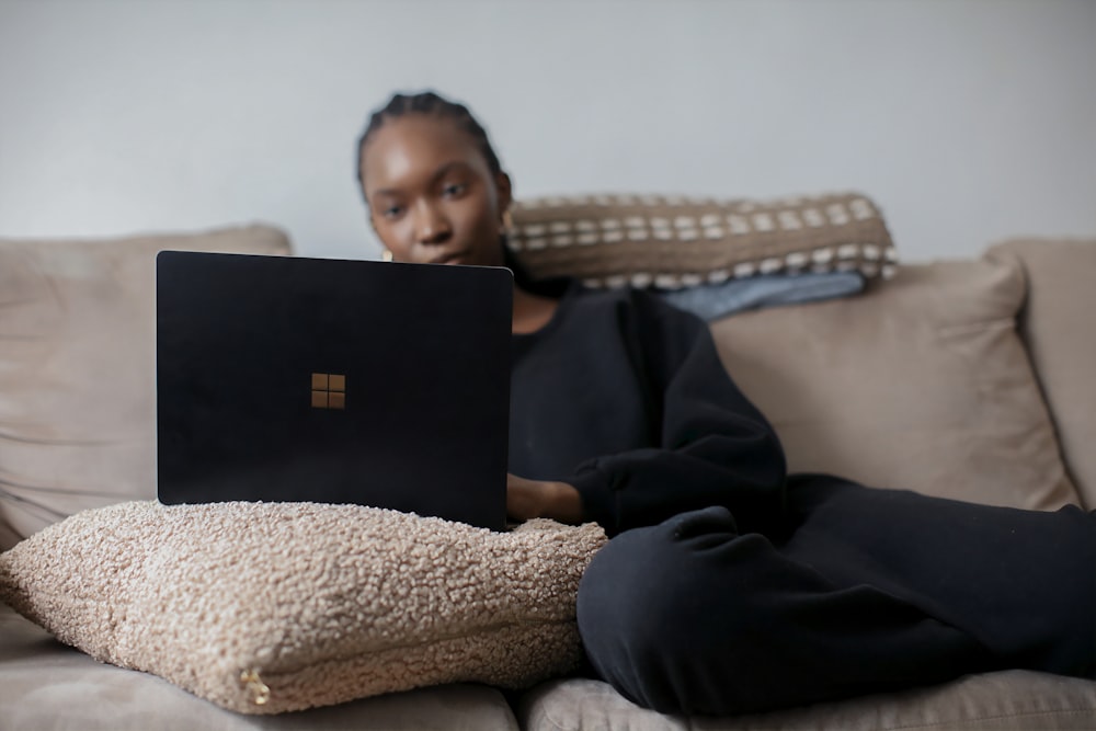 person sitting on couch using black Surface device