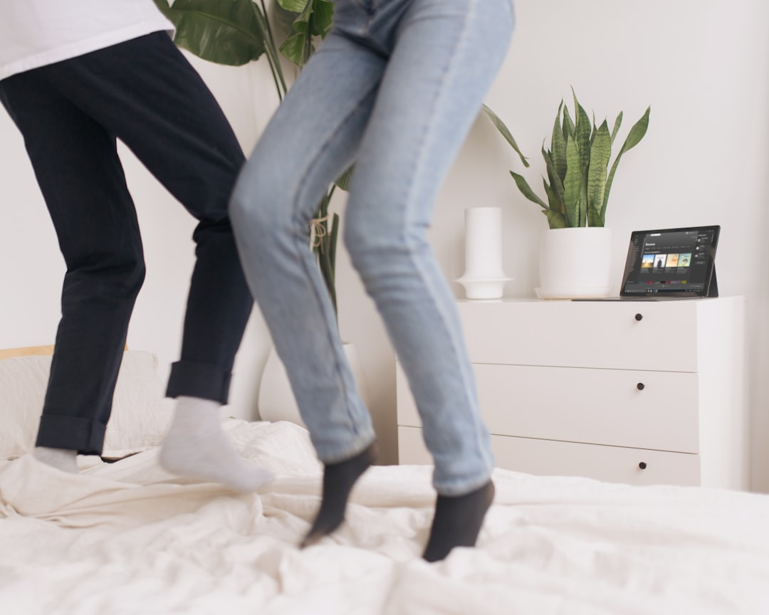 person in blue denim jeans and white socks standing on white bed