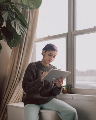 A serene morning scene with a person reading articles on a tablet by the window.