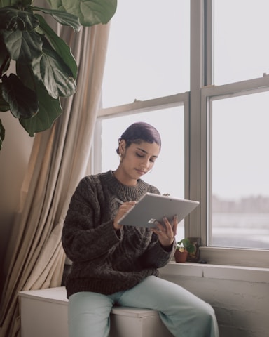 A cozy small business owner happily checking appointments on a sleek tablet with soft neutral and deep indigo tones in the background.