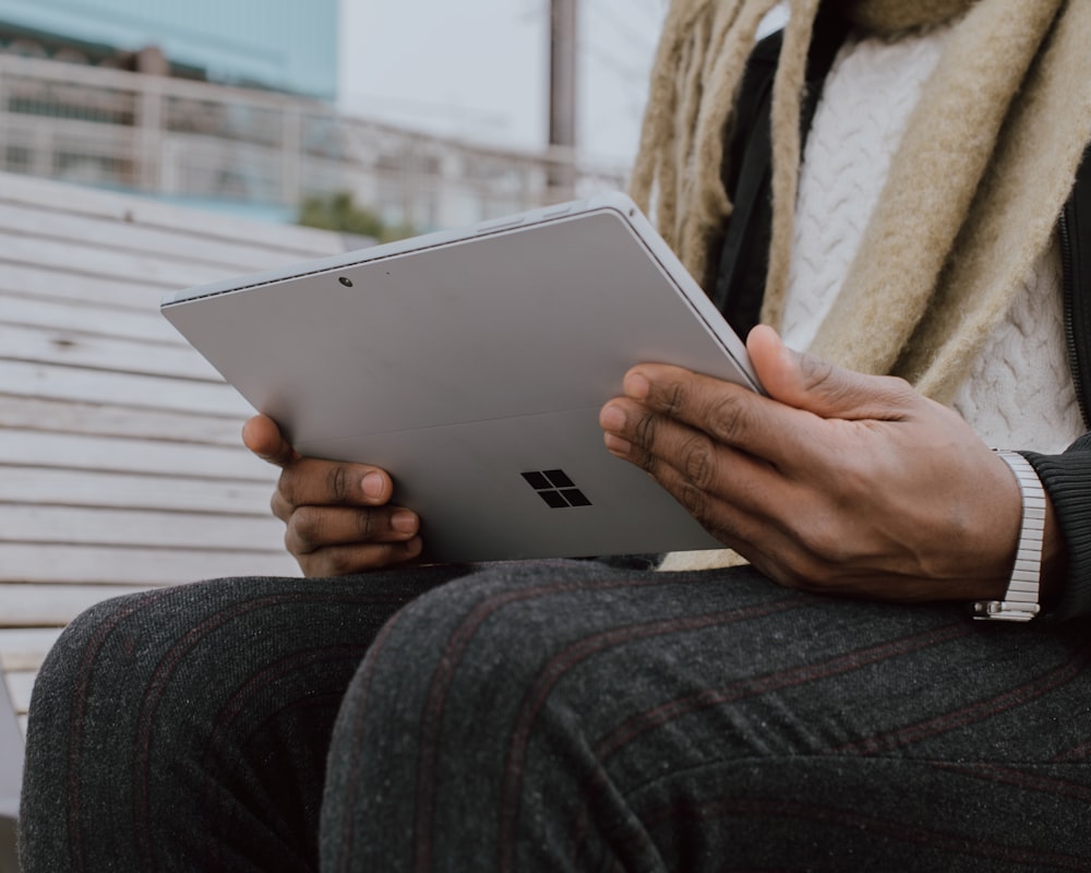 person in gray denim jeans holding Surface device