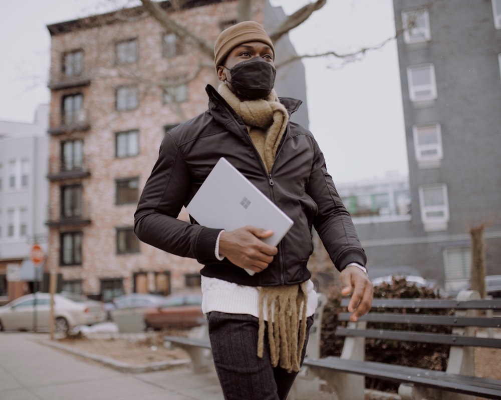 person in black jacket holding platinum Surface device