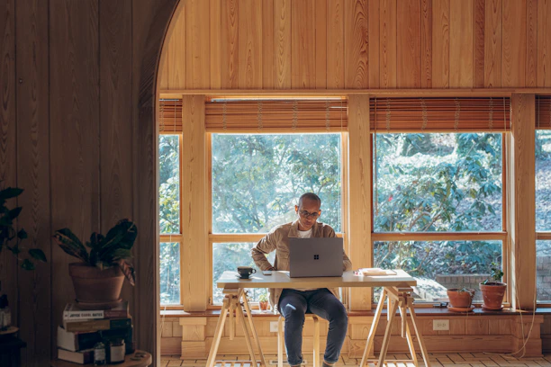 A cozy office desk with accounting books, a laptop, and a steaming cup of coffee by a window overlooking Vancouver.