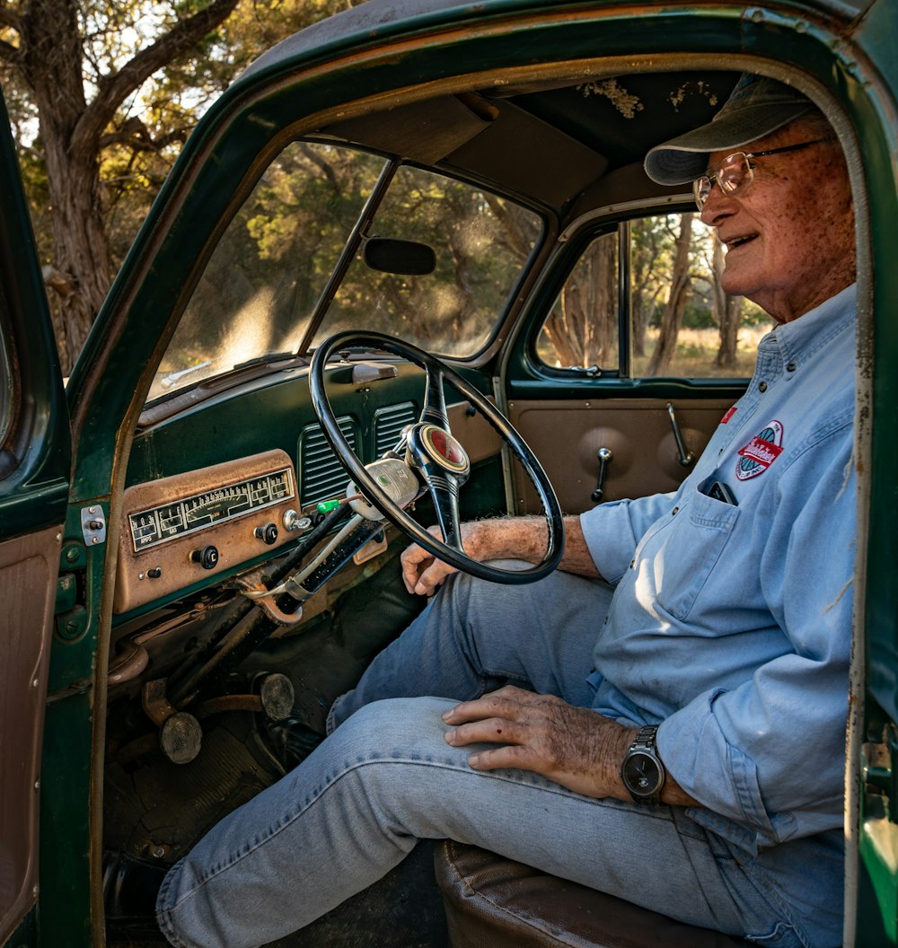 hombre con camisa azul abotonada conduciendo un automóvil durante el día