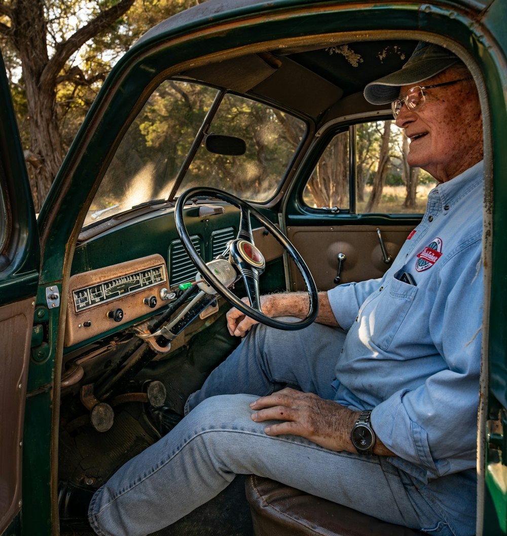 昼間に車を運転する青いボタンアップシャツを着た男