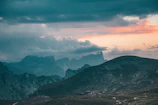 A serene landscape of rolling hills under a dramatic cloudy sky.